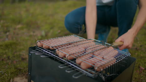 sausages-on-grill-man-is-cooking-outside-picnic-in-forest-camping-and-hiking-at-summer-vacation